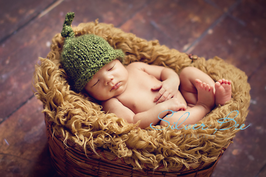 Green newborn boy hat sleeping in basket with faux fur Cedar Park Tx.