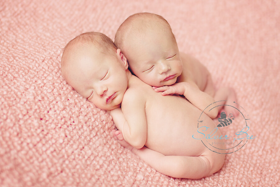 Identical Twin Newborn Girls Austin sleeping on a pink boucle blanket