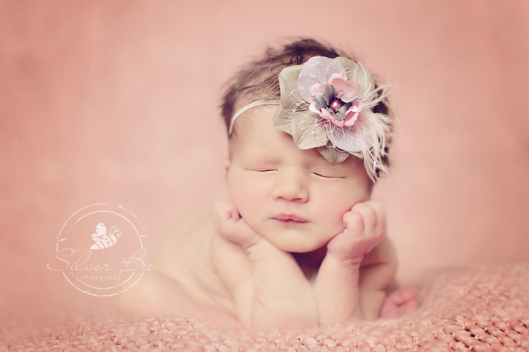 Austin newborn baby girl in forggie pose on pink bumby blanket with fancy pink and gray headband.