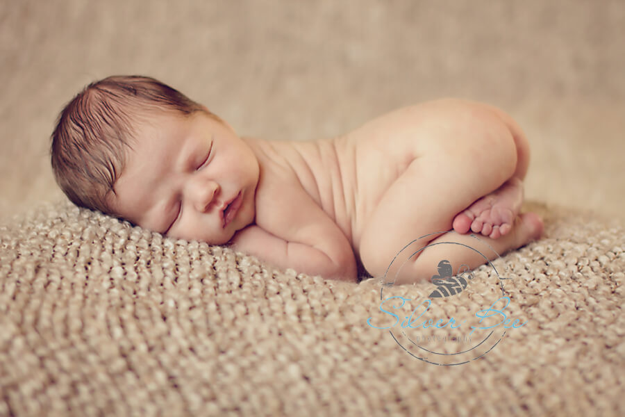 Austin newborn 6 day old baby boy sleeping on neutral texture blanket in tushie pose.