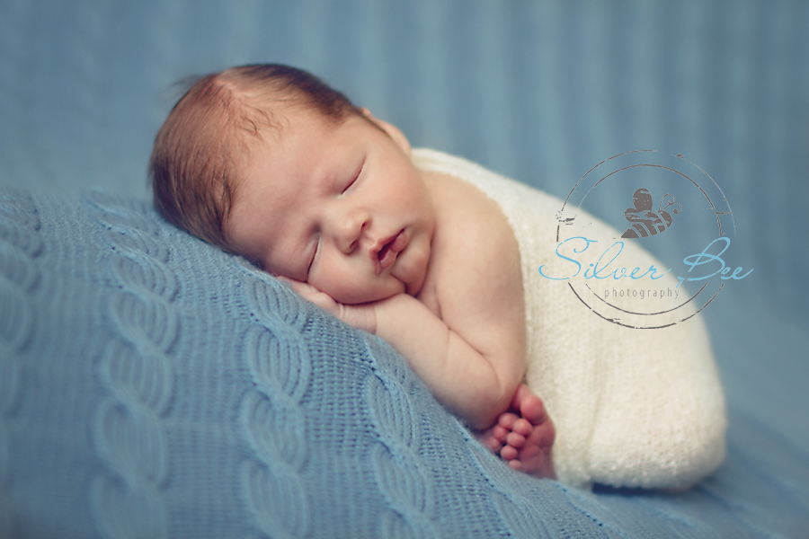 Austin newborn photographer baby boy sleeping with stretch wrap and blue cable blanket.