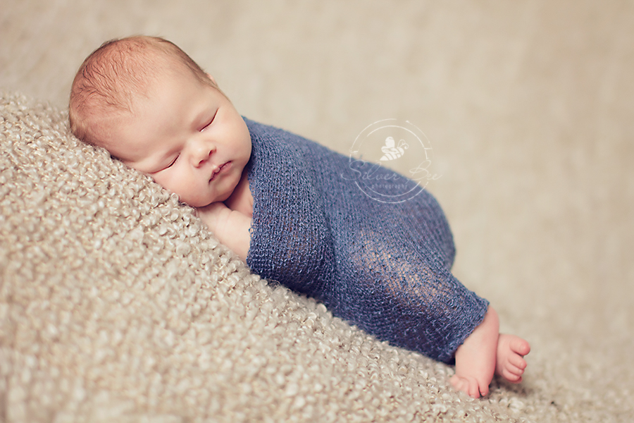 Austin seven day old baby boy sleeping for newborn photo session with brown boucle blanket and denim blue stretch newborn wrap.