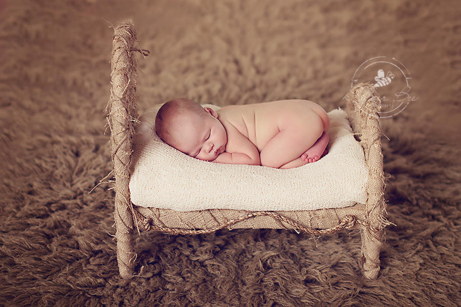 Newborn Photo session in Austin with boy sleeping on burlap newborn bed prop with brown flokati rug.