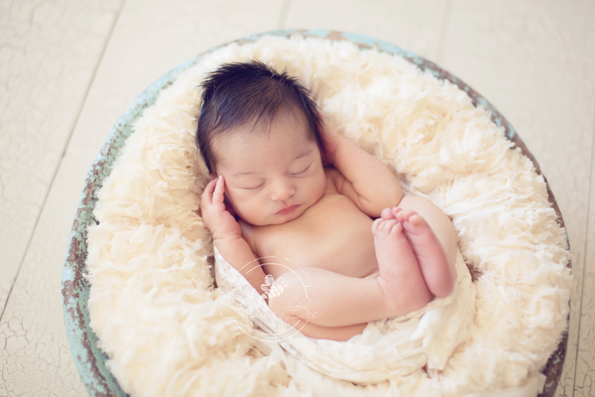 Newborn baby girl sleeping in blue bown at photo session in Austin Texas