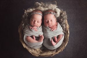 twin baby girls swaddled in gray wrap | Silver Bee Photography