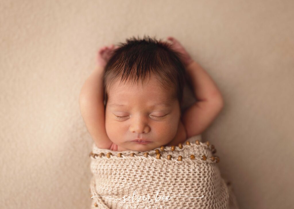 luxury newborn portraits, Newborn baby boy sleeping with arms up and swaddled.